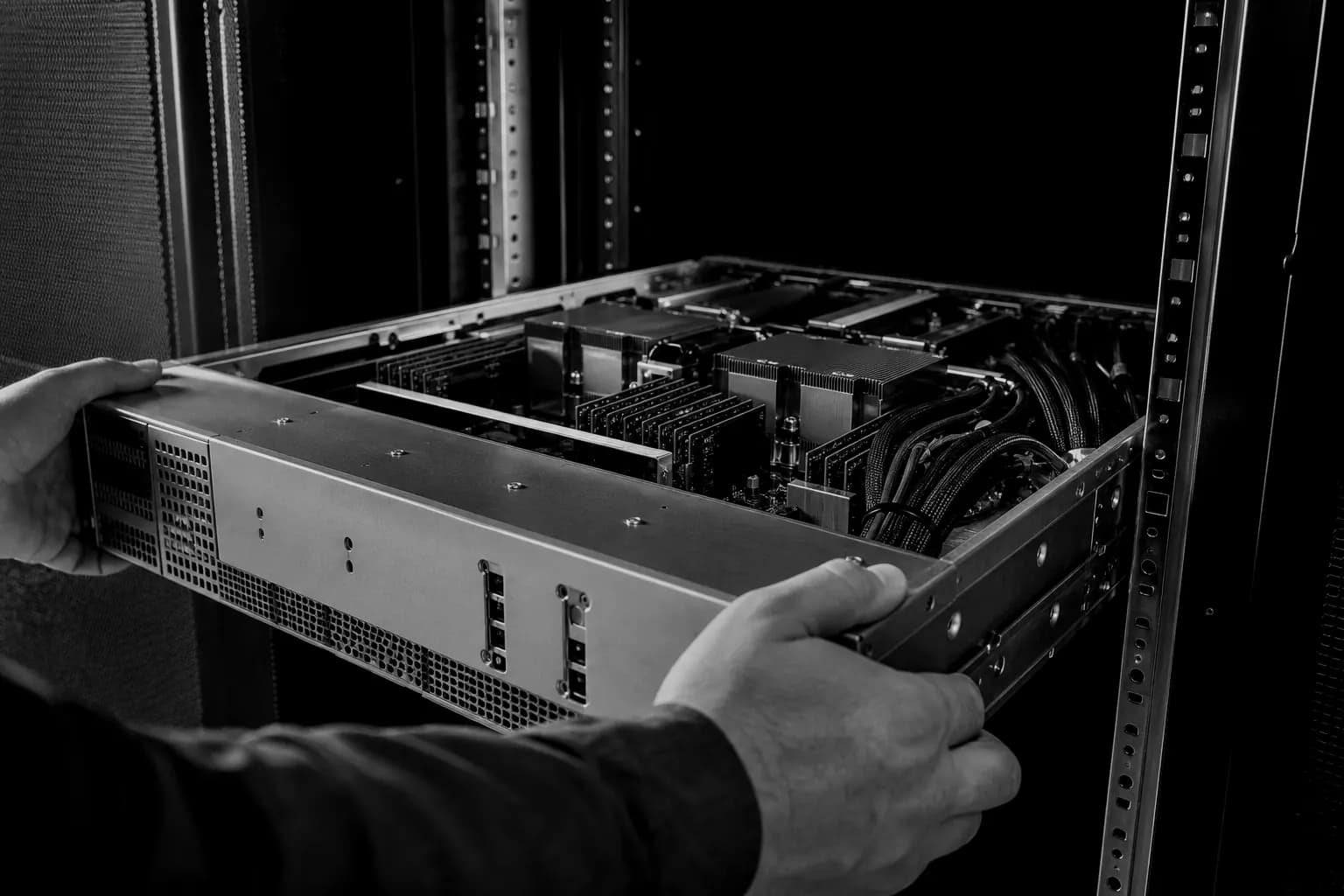 Engineer seating a bare-metal server chassis onto its rails inside a rack